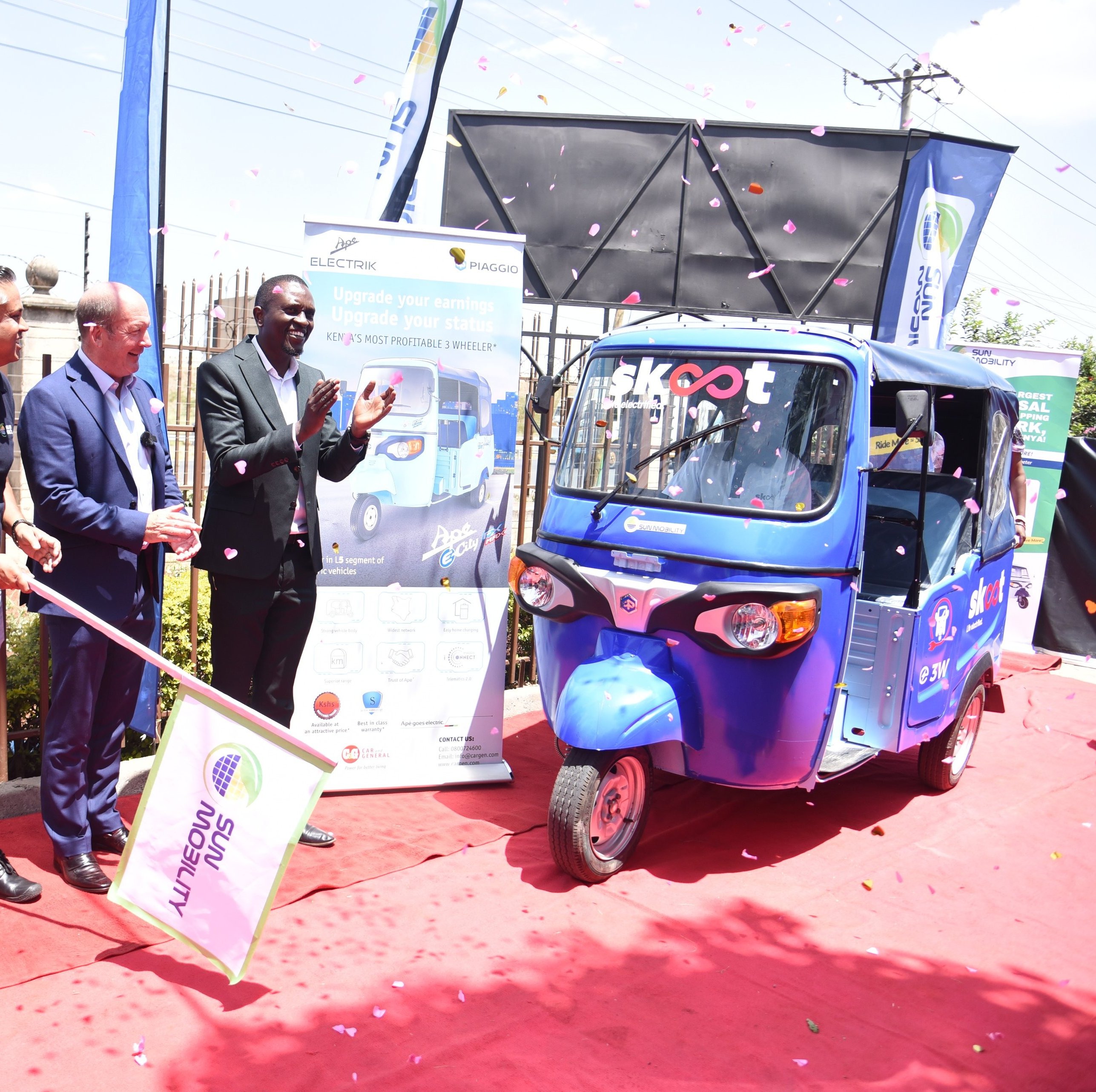 People waving flags at a Tuk Tuk