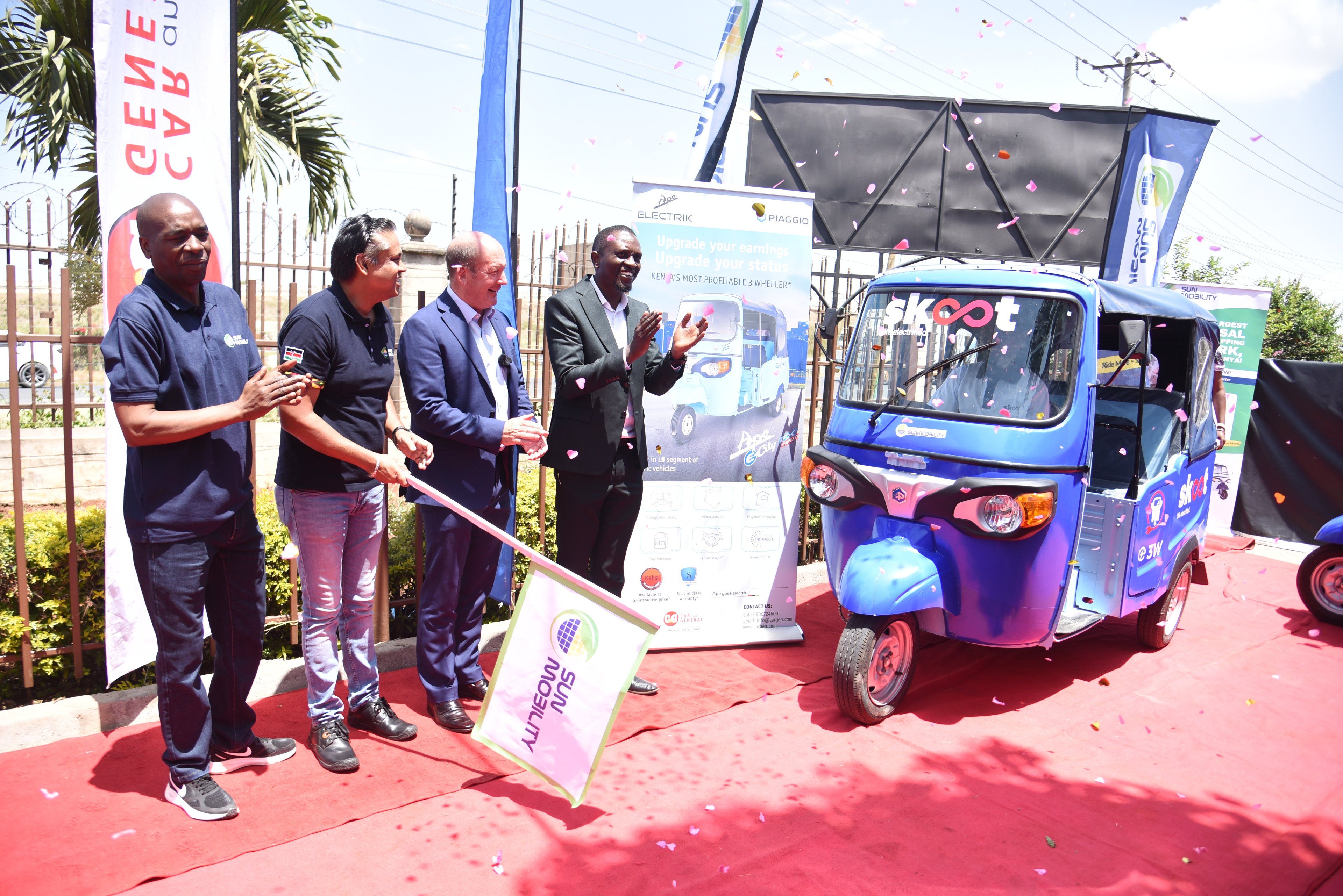 People waving flags at a tuk tuk