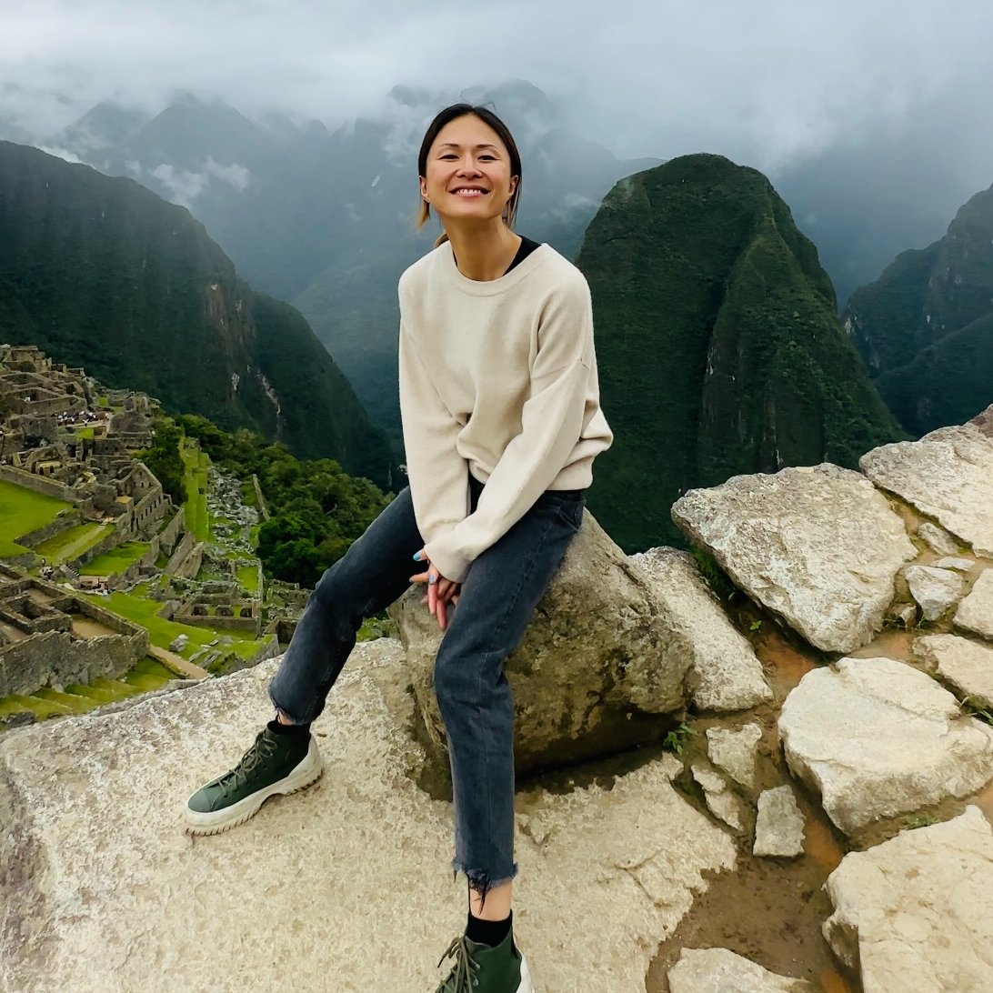 Lady on top of Machu Picchu in white jumper