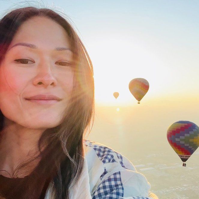 Woman in  desert with hot air ballons in background