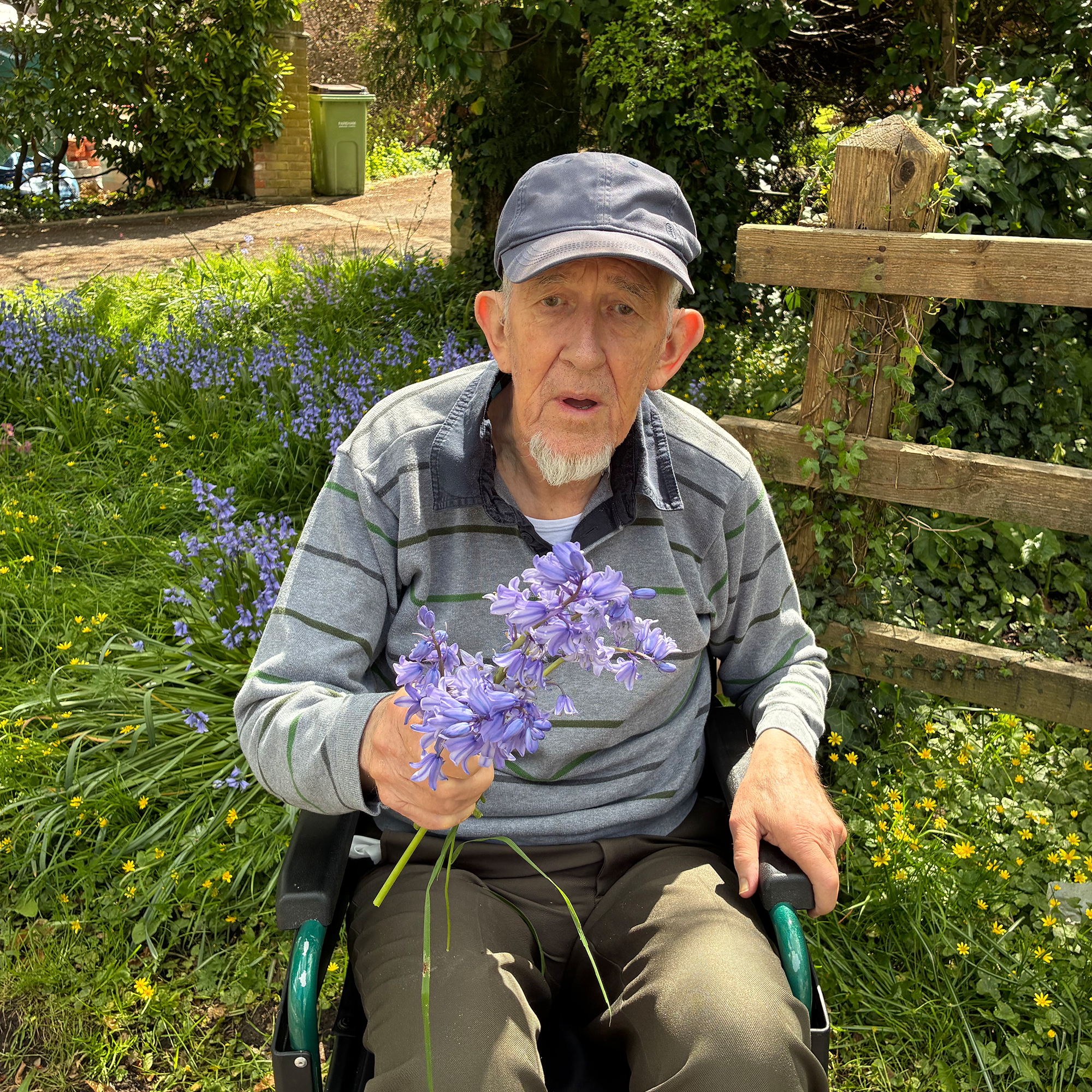 A Blackbrook House Resident collecting bluebells in the landscaped garden